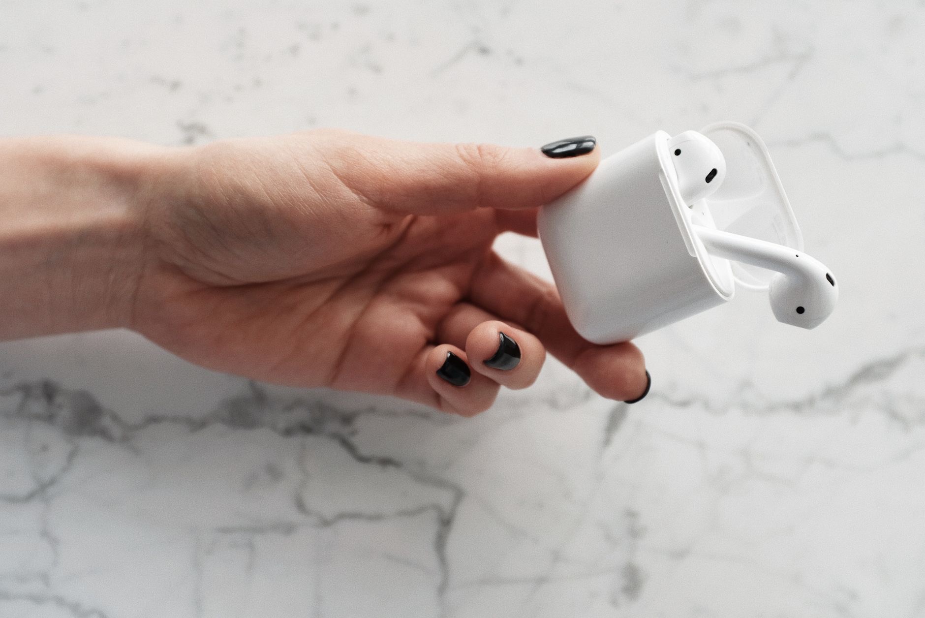 A wireless earbud and case held in a hand