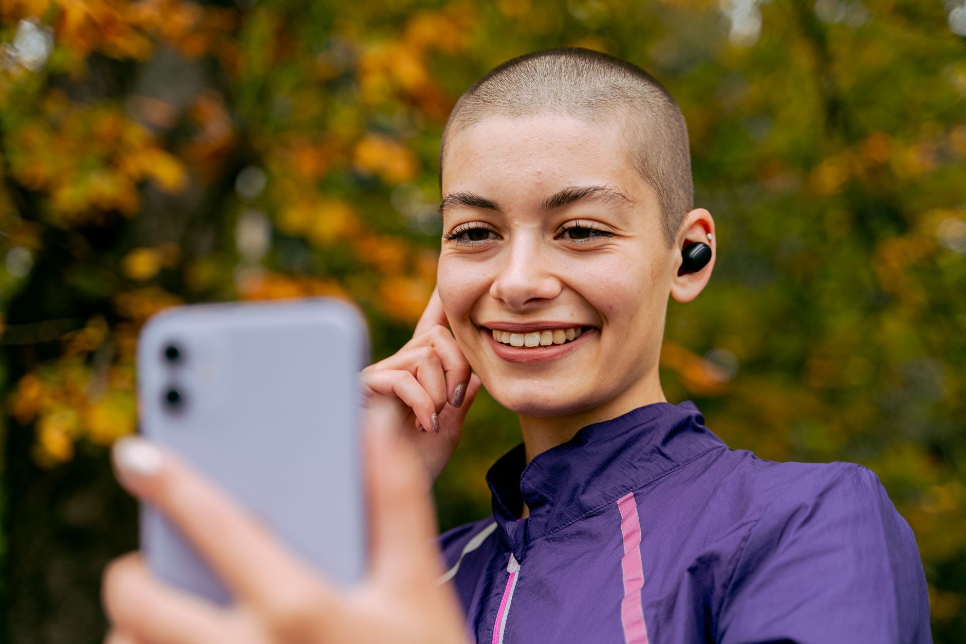 Person wearing wireless earbuds during a phone call outdoors