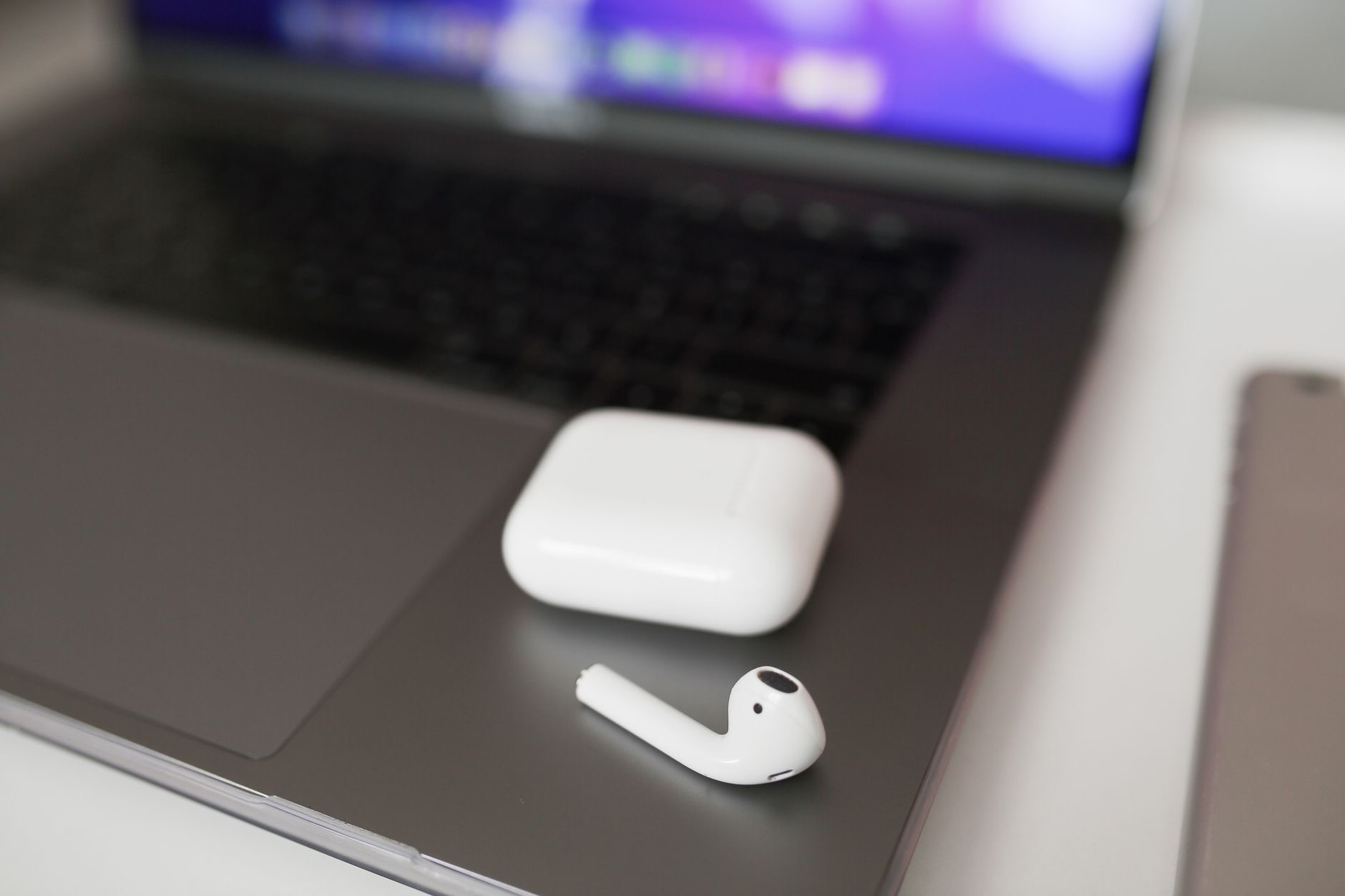 Wireless earbuds beside a laptop on a desk