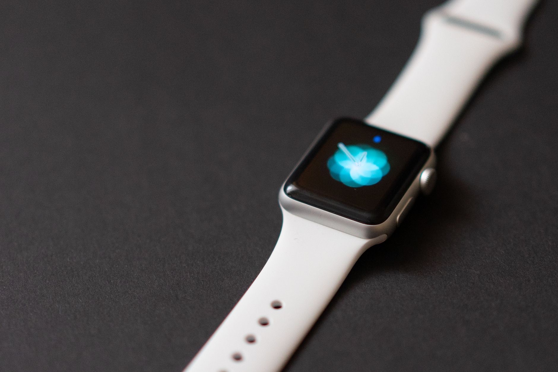 Apple Watch with a variety of colorful bands displayed on a white surface