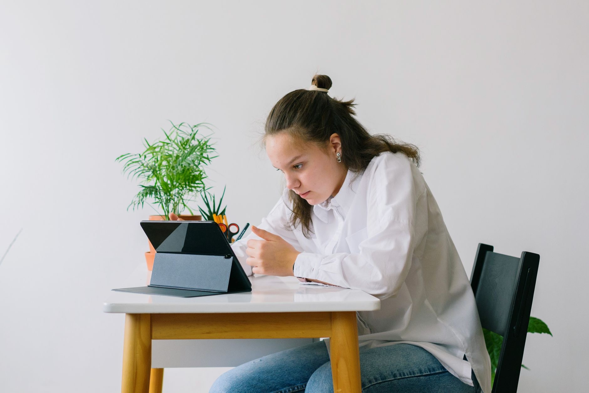 Student using a tablet at a desk with books