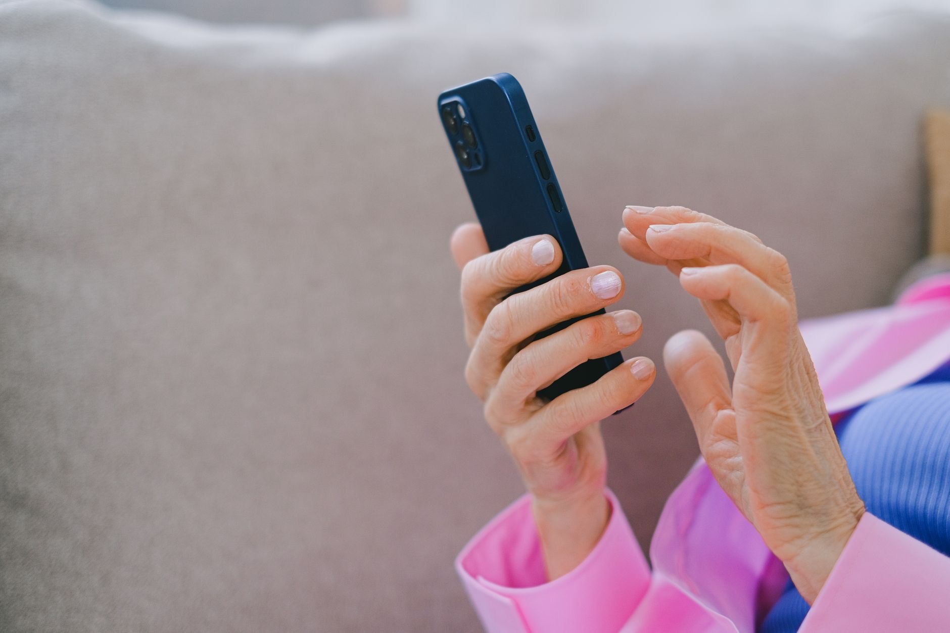 An older person holding a phone in both hands