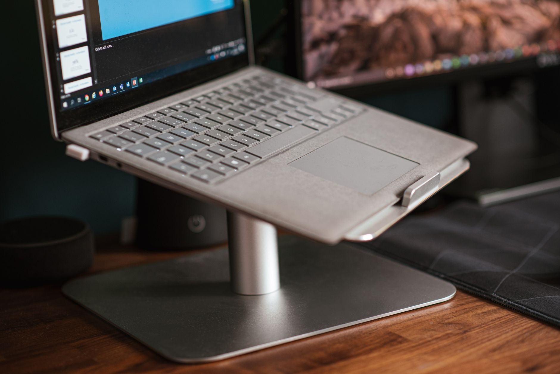 Laptop elevated on a aluminum stand with keyboard below