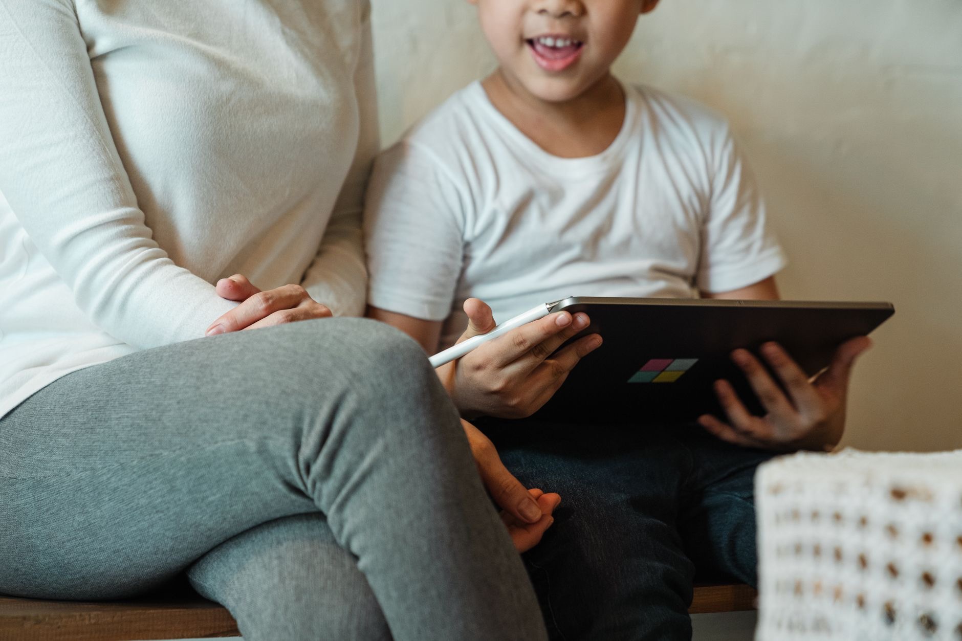 Child using a tablet while a parent supervises nearby