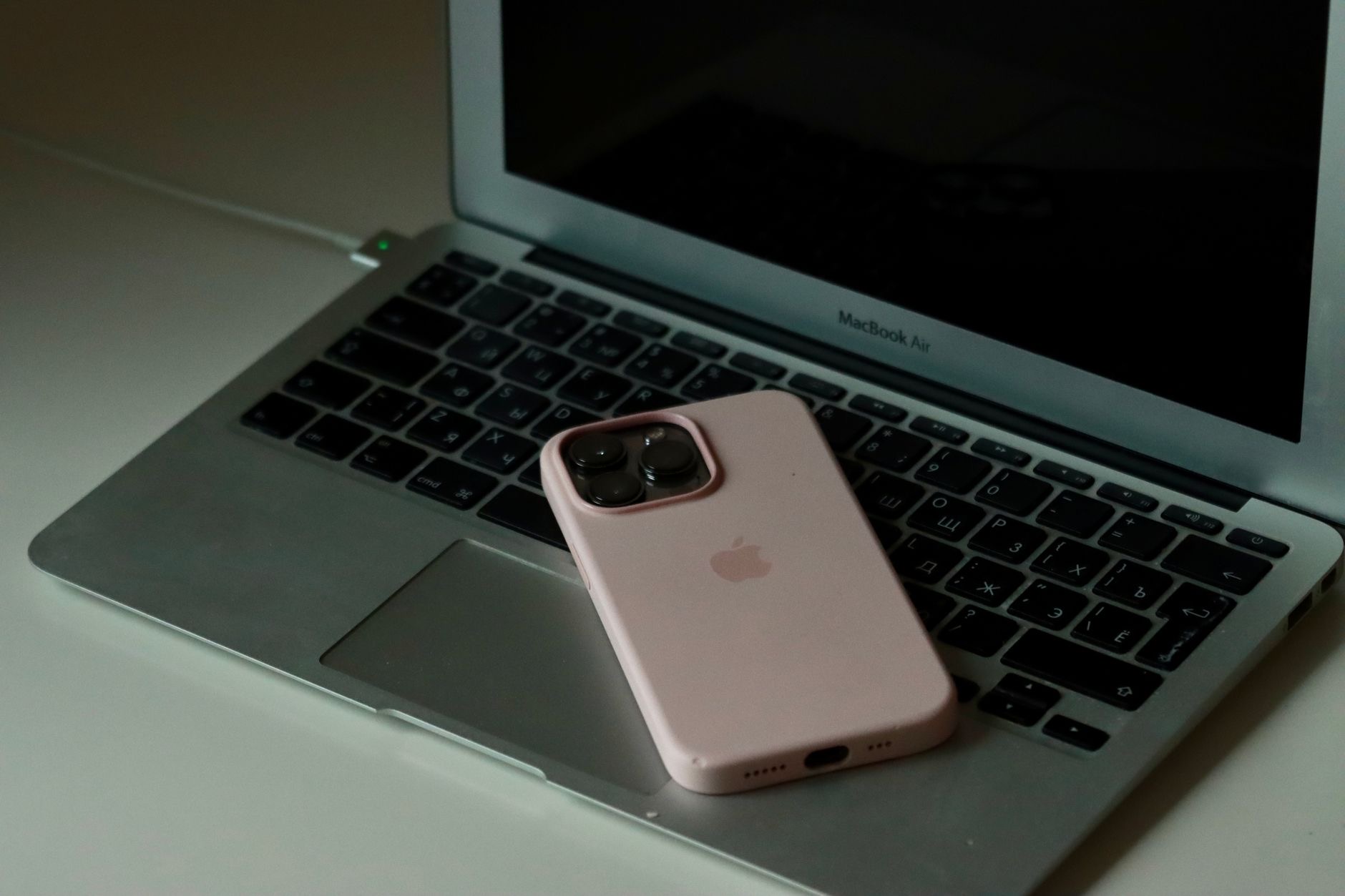 iPhone connected to a laptop with a cable on a wooden desk