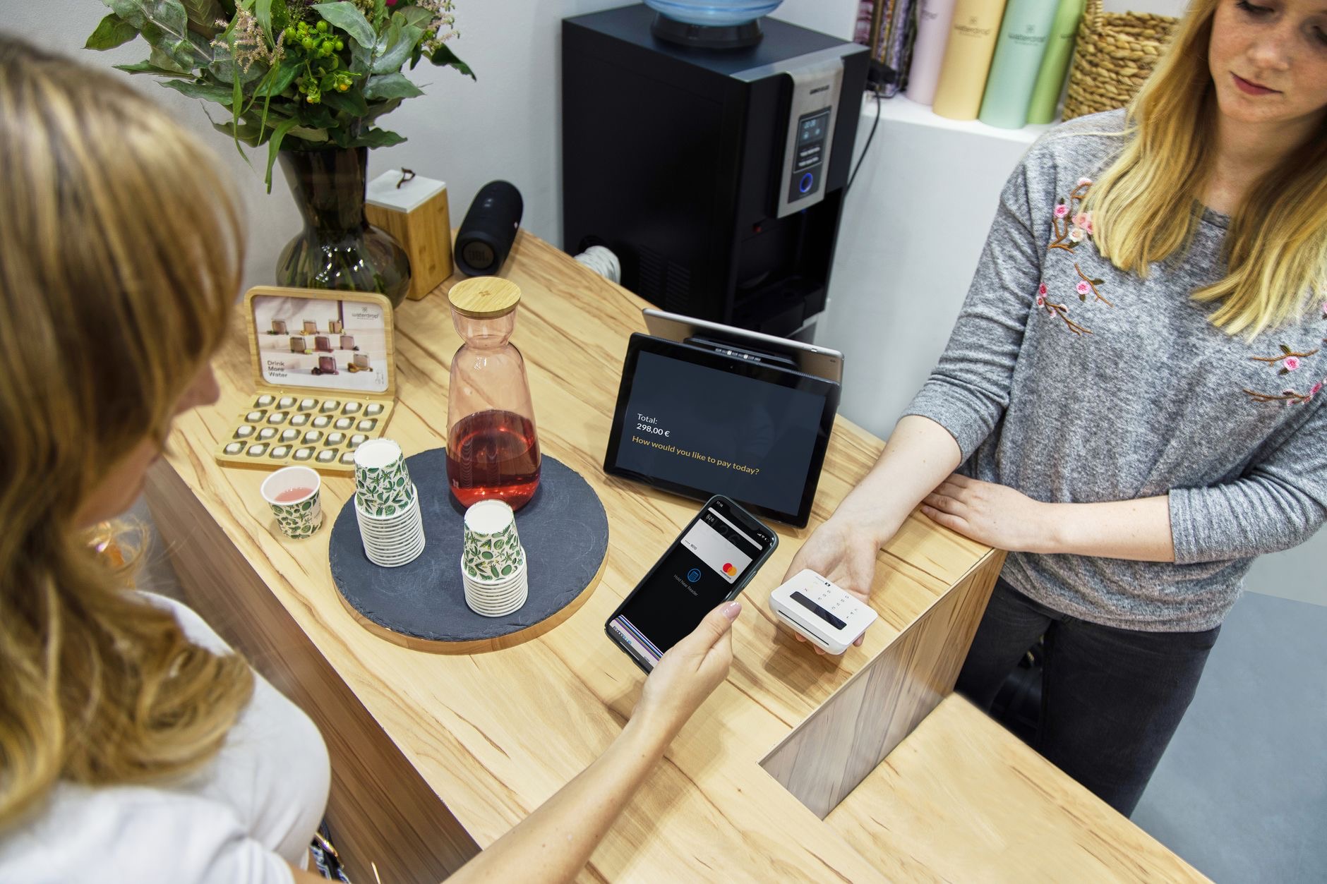 Person holding an iPhone near a contactless payment terminal in a store
