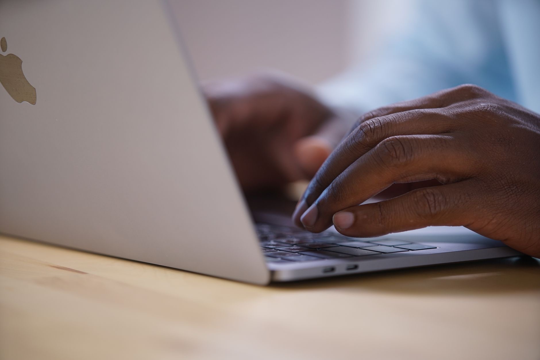 Person using a MacBook at a desk near a window