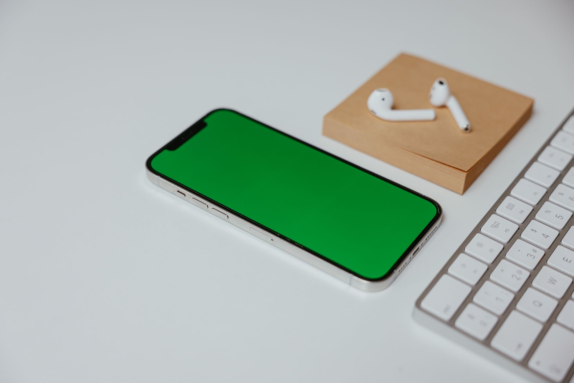 A phone on a desk with earbuds